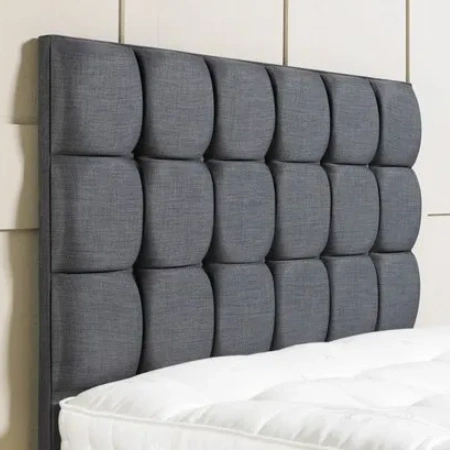 Grey buttoned upholstered headboard above a mattress