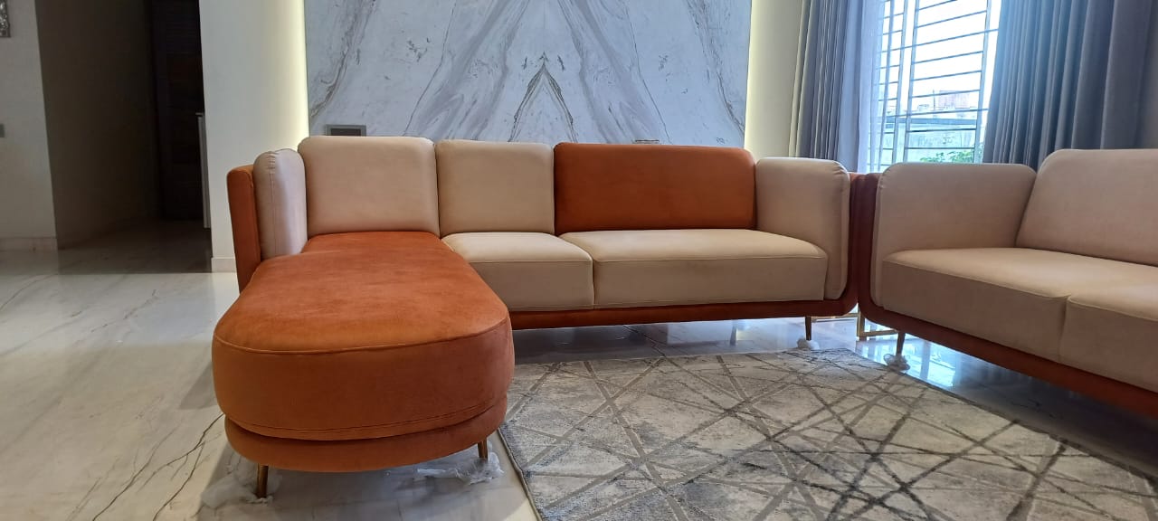 Orange and cream sectional sofa against a marble wall